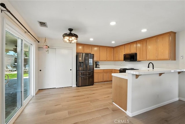 23885 Cheyenne Canyon Dr, Menifee, CA 92587 - kitchen featuring black appliances, a peninsula, light wood-style flooring, recessed lighting, and a breakfast bar