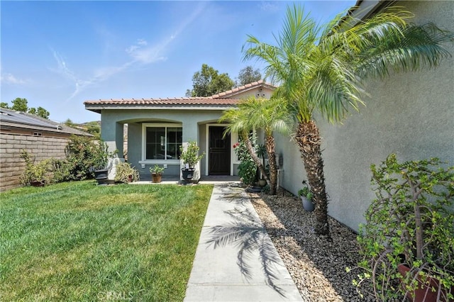23885 Cheyenne Canyon Dr, Menifee, CA 92587 - view of exterior entry with stucco siding, a yard, and a tile roof