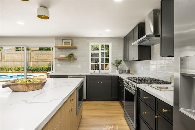 121 W Borromeo Ave, Placentia, CA 92870 - kitchen with wall chimney range hood, stainless steel appliances, light wood-style floors, tasteful backsplash, and light stone counters