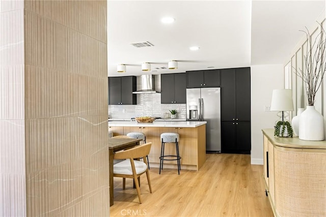 121 W Borromeo Ave, Placentia, CA 92870 - kitchen with stainless steel fridge, dark cabinetry, wall chimney exhaust hood, a kitchen bar, and light countertops
