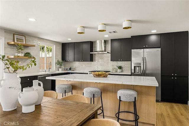 121 W Borromeo Ave, Placentia, CA 92870 - kitchen with wall chimney range hood, appliances with stainless steel finishes, dark cabinets, a center island, and a breakfast bar area