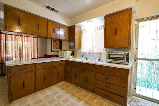 937 E 6th St, Madera, CA 93638 - kitchen with white microwave, brown cabinetry, and light countertops