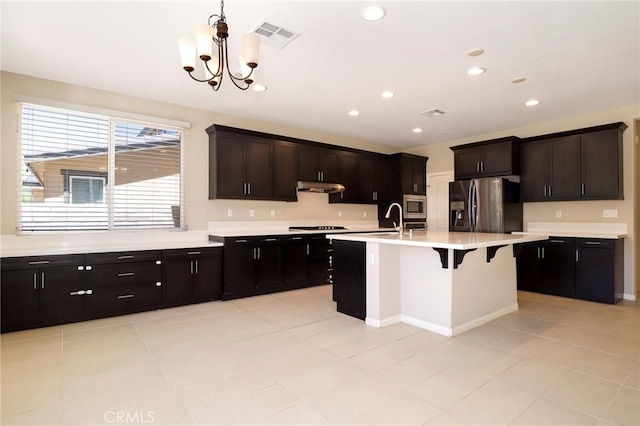 28245 Nield Ct, Saugus, CA 91350 - kitchen featuring appliances with stainless steel finishes, light countertops, a chandelier, decorative light fixtures, and a breakfast bar area