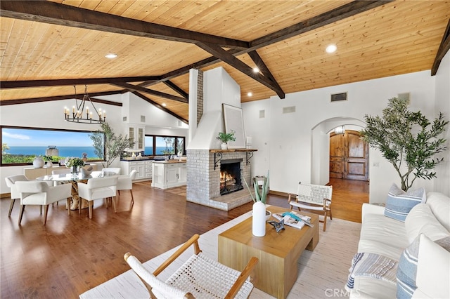 2575 Temple Hills Dr, Laguna Beach, CA 92651 - living room with arched walkways, a wood ceiling with exposed beams, a chandelier, a brick fireplace, and wood finished floors