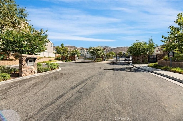7346 Garnet Ridge Rd, Jurupa Valley, CA 92509 - view of asphalt road with a residential view, sidewalks, a gate, a gated entry, and curbs