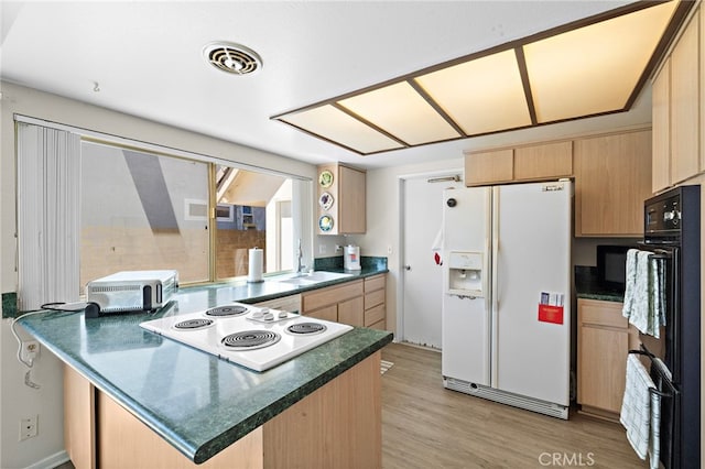 20822 Skimmer Ln, Huntington Beach, CA 92646 - kitchen featuring white appliances, light brown cabinetry, a peninsula, dark countertops, and light wood-style flooring
