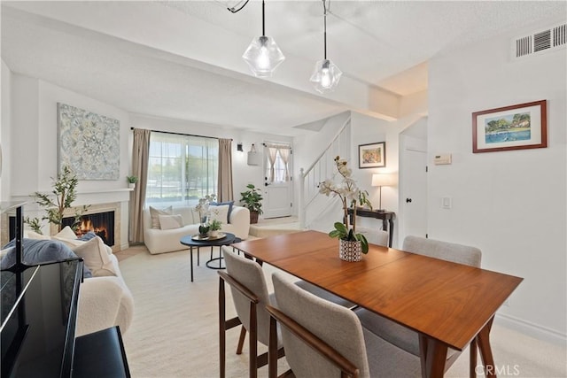 53 Misty Run Unit 10, Irvine, CA 92614 - dining space with stairs, a warm lit fireplace, and light carpet