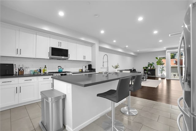 2930 Rowena Ave Unit 4, Los Angeles, CA 90039 - kitchen featuring stainless steel appliances, dark countertops, recessed lighting, a kitchen bar, and tasteful backsplash