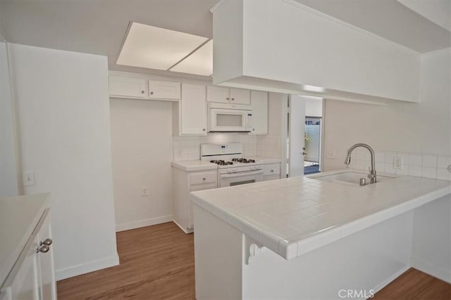 1138 N Valley St, Burbank, CA 91505 - kitchen with white appliances, a peninsula, wood finished floors, tasteful backsplash, and tile countertops