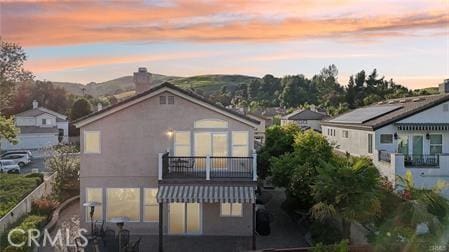 14213 Aliso Ct, Chino Hills, CA 91709 - back of property at dusk featuring a balcony, stucco siding, and a chimney