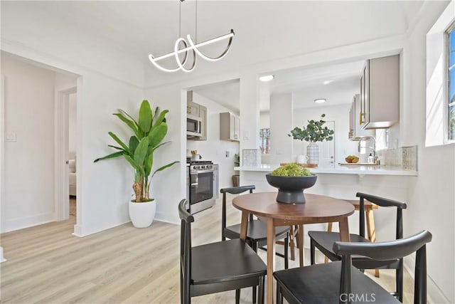215 E 107th St, Los Angeles, CA 90003 - dining area featuring light wood-type flooring and a chandelier