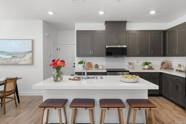766 Makani St Unit 1, Chula Vista, CA 91911 - kitchen with stainless steel microwave, a kitchen breakfast bar, light countertops, light wood-type flooring, and recessed lighting