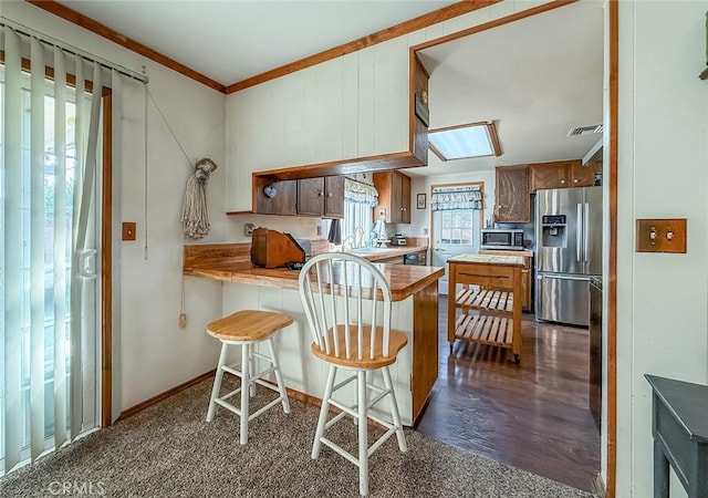 2191 Hilldale Ave, Simi Valley, CA 93063 - kitchen with appliances with stainless steel finishes, a peninsula, crown molding, brown cabinetry, and a breakfast bar