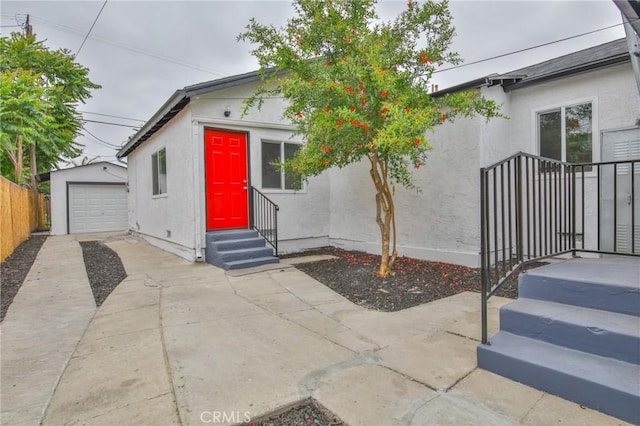 343 E 98th St, Los Angeles, CA 90003 - view of front facade with stucco siding, driveway, an outbuilding, entry steps, and a garage