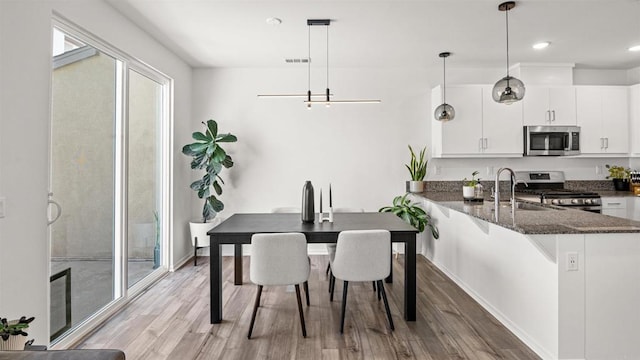 220 Perennial Pl, Fallbrook, CA 92028 - kitchen with stainless steel appliances, light wood-type flooring, white cabinetry, dark stone counters, and a peninsula