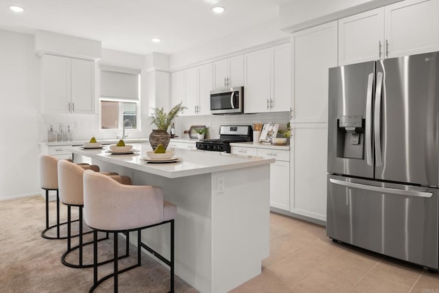 2310 Stardust Gln, Escondido, CA 92025 - kitchen with appliances with stainless steel finishes, a kitchen breakfast bar, a kitchen island, white cabinetry, and backsplash