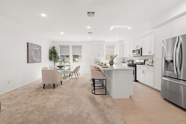 2310 Stardust Gln, Escondido, CA 92025 - kitchen with appliances with stainless steel finishes, white cabinetry, a center island, a kitchen bar, and light countertops