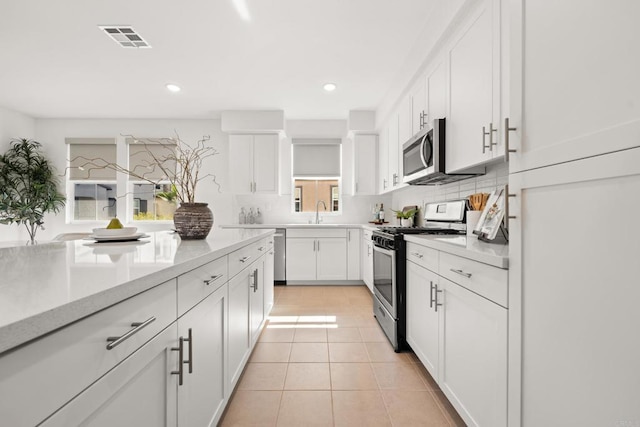 2310 Stardust Gln, Escondido, CA 92025 - kitchen with appliances with stainless steel finishes, white cabinets, light countertops, recessed lighting, and backsplash