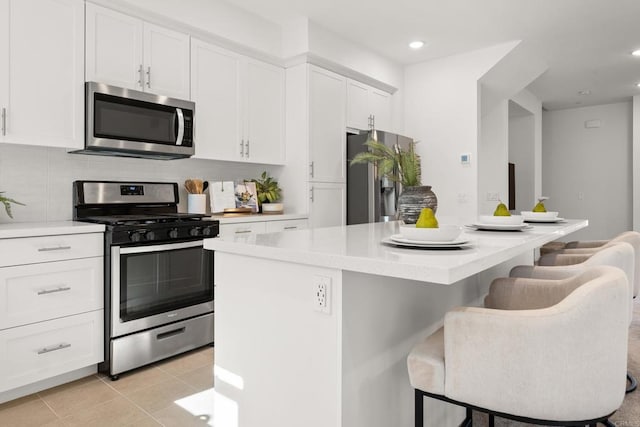 2310 Stardust Gln, Escondido, CA 92025 - kitchen featuring appliances with stainless steel finishes, white cabinets, a center island, a kitchen breakfast bar, and light countertops