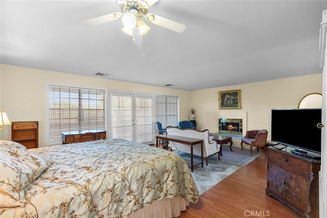4790 Adam Rd, Simi Valley, CA 93063 - bedroom featuring multiple windows, wood finished floors, a glass covered fireplace, and ceiling fan