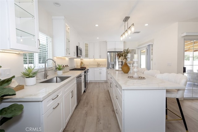 15256 Clymer St, San Fernando, CA 91345 - kitchen featuring stainless steel appliances, a kitchen breakfast bar, a center island, glass insert cabinets, and white cabinets
