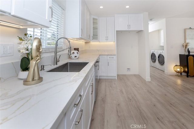 15256 Clymer St, San Fernando, CA 91345 - kitchen featuring washing machine and clothes dryer, white cabinetry, light stone counters, glass insert cabinets, and light wood finished floors