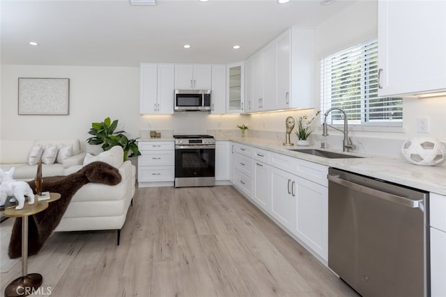 15256 Clymer St, San Fernando, CA 91345 - kitchen featuring appliances with stainless steel finishes, white cabinets, light stone counters, light wood-style flooring, and glass insert cabinets
