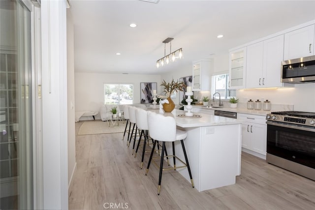 15256 Clymer St, San Fernando, CA 91345 - kitchen featuring stainless steel appliances, a kitchen bar, healthy amount of natural light, light wood finished floors, and recessed lighting