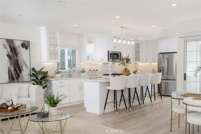 15256 Clymer St, San Fernando, CA 91345 - kitchen with stainless steel appliances, a kitchen bar, plenty of natural light, light wood-style floors, and recessed lighting