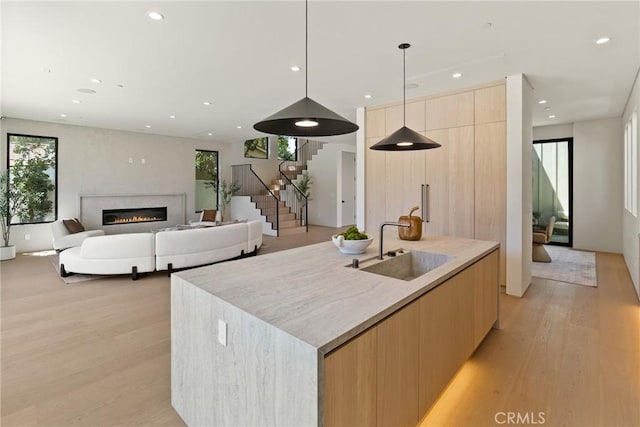 14738 Otsego St, Sherman Oaks, CA 91403 - kitchen with modern cabinets, light wood-type flooring, a center island with sink, a glass covered fireplace, and light brown cabinets