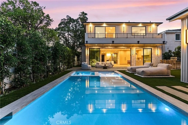 14738 Otsego St, Sherman Oaks, CA 91403 - back of house at dusk with a balcony, outdoor lounge area, a pool with connected hot tub, and a patio area