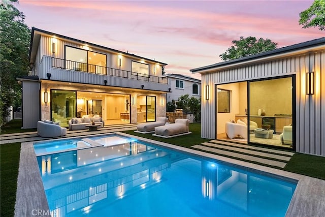 14738 Otsego St, Sherman Oaks, CA 91403 - back of property at dusk featuring a balcony, an outdoor living space, an outdoor pool, and board and batten siding