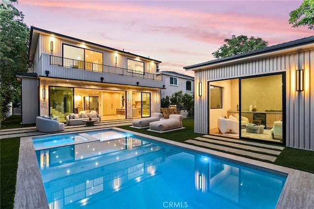 14738 Otsego St, Sherman Oaks, CA 91403 - back of property at dusk with a balcony, an outdoor living space, an outdoor pool, and board and batten siding