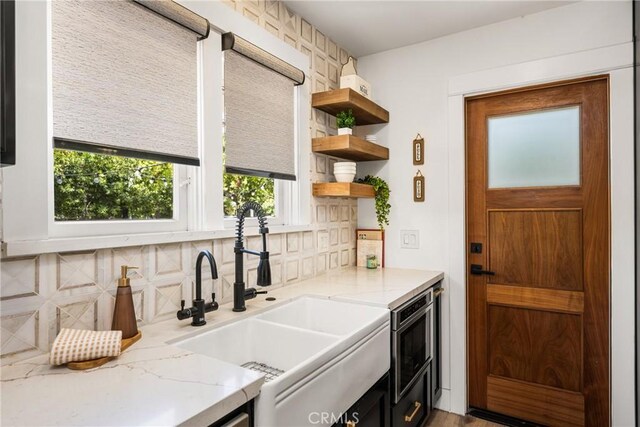 705 E Palm Ave, Orange, CA 92866 - kitchen featuring decorative backsplash, open shelves, light stone countertops, stainless steel microwave, and dark cabinetry