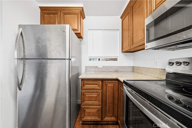 1629 Cherry Ave Unit 102, Long Beach, CA 90813 - kitchen featuring appliances with stainless steel finishes, light countertops, brown cabinetry, and dark wood finished floors