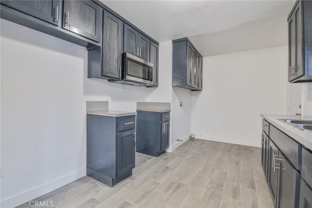 9218 Hooper Ave, Los Angeles, CA 90002 - kitchen featuring stainless steel microwave, light wood finished floors, and light countertops