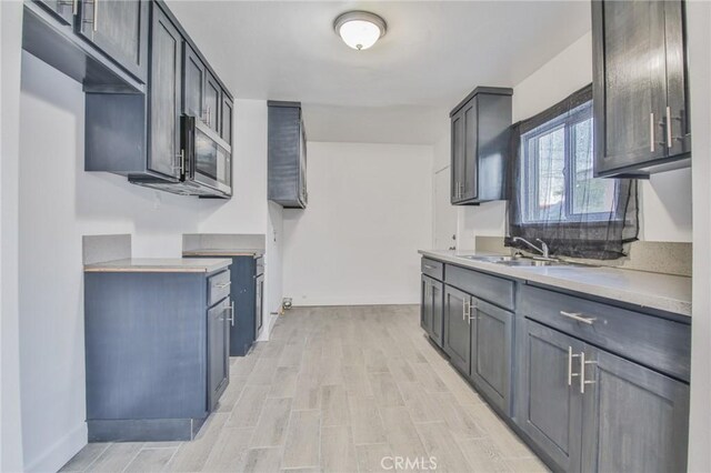 9218 Hooper Ave, Los Angeles, CA 90002 - kitchen featuring stainless steel microwave, light wood-type flooring, and light countertops