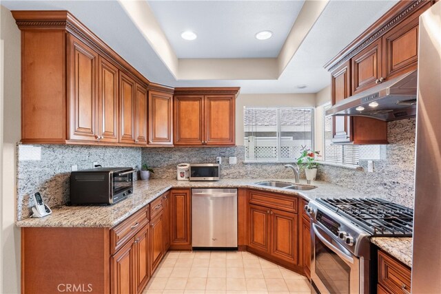 17300 Azalea Ct, La Puente, CA 91744 - kitchen with stainless steel appliances, brown cabinetry, under cabinet range hood, and backsplash