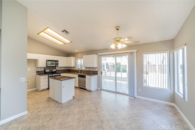 1870 S Jasmin Ct, Loma Linda, CA 92354 - kitchen with appliances with stainless steel finishes, healthy amount of natural light, dark countertops, vaulted ceiling, and white cabinets