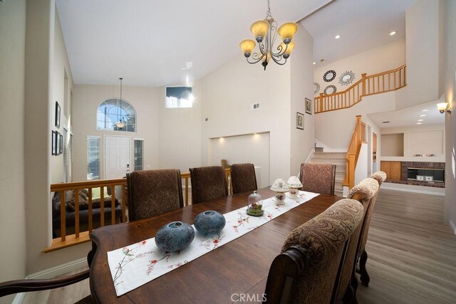 27829 Coldsprings Pl, Valencia, CA 91354 - dining room featuring a chandelier, stairs, high vaulted ceiling, wood finished floors, and a glass covered fireplace