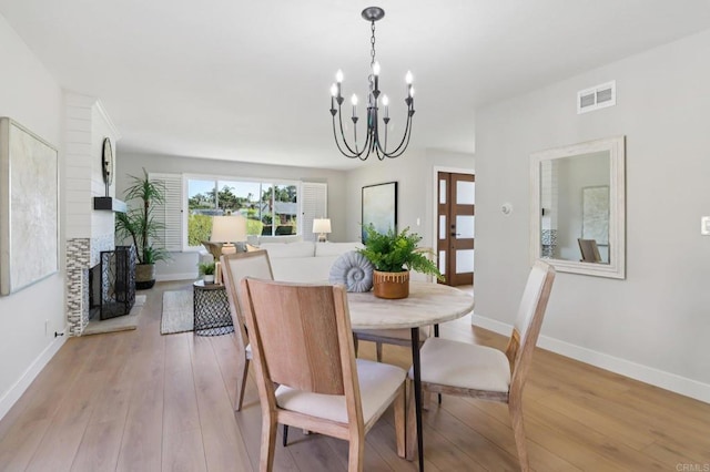 1358 Walnutview Dr, Encinitas, CA 92024 - dining room with light wood-style flooring, a chandelier, and a fireplace with raised hearth