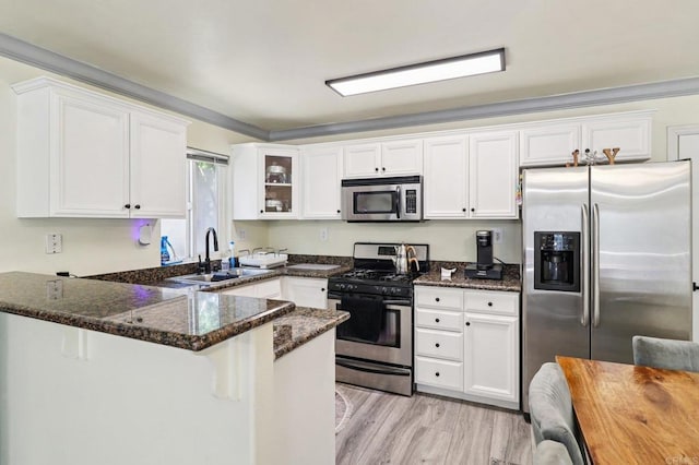 8980 Lamar St # 6, Spring Valley, CA 91977 - kitchen featuring appliances with stainless steel finishes, a peninsula, dark stone counters, white cabinets, and light wood-style floors