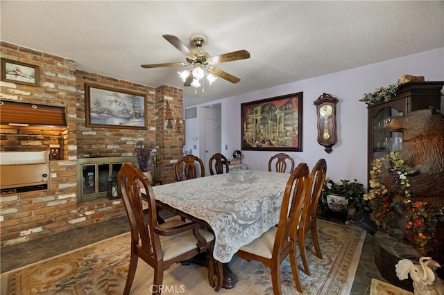 341 Mellane Cir, Orland, CA 95963 - dining area with ceiling fan, a fireplace, a textured ceiling, and brick wall