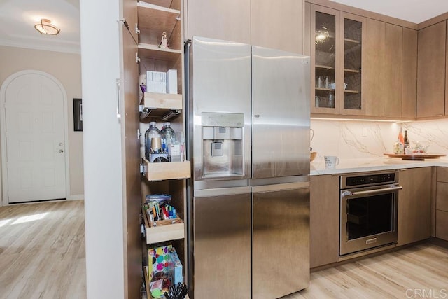 2740 E Bainbridge Rd, San Diego, CA 92106 - kitchen featuring appliances with stainless steel finishes, light wood-style floors, crown molding, tasteful backsplash, and glass insert cabinets