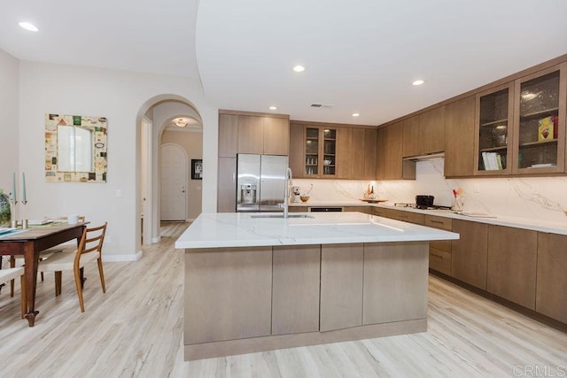 2740 E Bainbridge Rd, San Diego, CA 92106 - kitchen featuring brown cabinets, cooktop, stainless steel fridge with ice dispenser, arched walkways, and a kitchen island with sink
