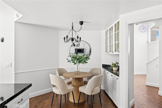 18 Saint Thomas, Laguna Niguel, CA 92677 - dining space with dark wood-type flooring, a wainscoted wall, a textured ceiling, and a chandelier