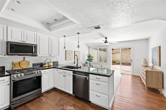18 Saint Thomas, Laguna Niguel, CA 92677 - kitchen featuring stainless steel appliances, a peninsula, white cabinets, dark wood finished floors, and crown molding