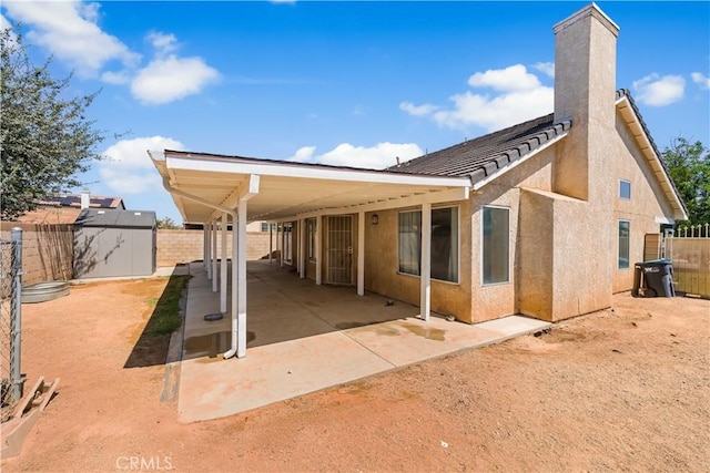 2019 Greentree St, Lancaster, CA 93535 - rear view of property with a storage unit, stucco siding, a fenced backyard, a patio area, and a chimney