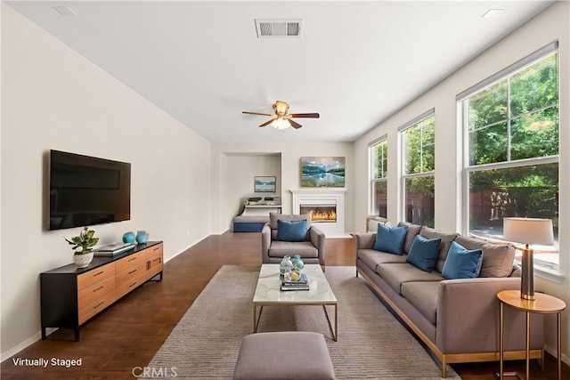 39886 Worthington Pl, Temecula, CA 92591 - living area with healthy amount of natural light, ceiling fan, a warm lit fireplace, and dark wood-type flooring
