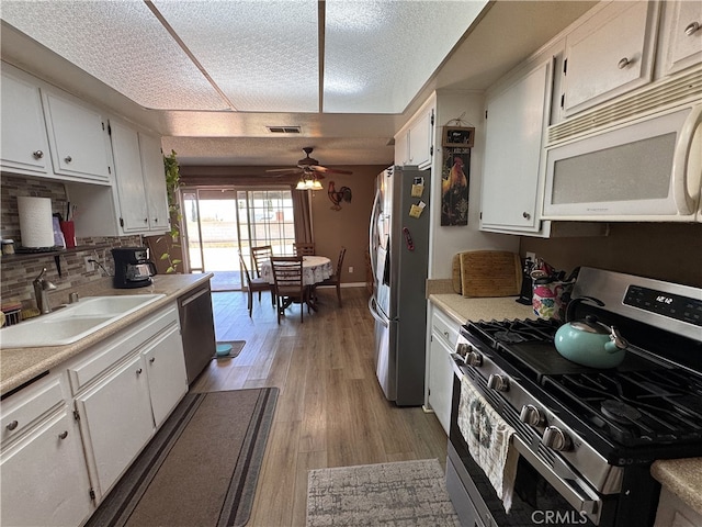 811 Mescal Dr, Barstow, CA 92311 - kitchen with appliances with stainless steel finishes, light countertops, white cabinets, and a textured ceiling